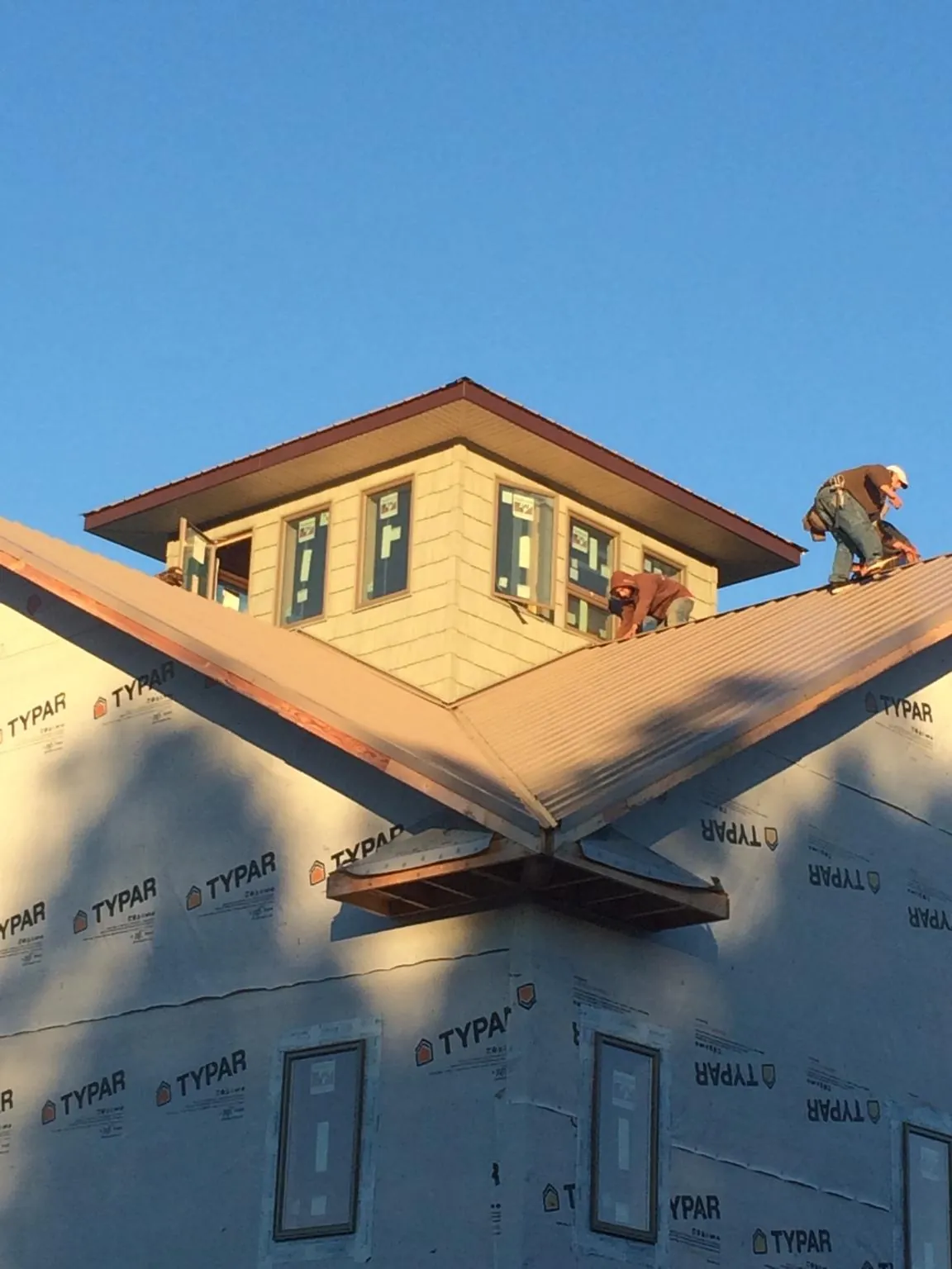 Roofers working around a rooftop cupola on a new metal roof at sunset — Roof Waterproofing in Winchester by Roofing Brothers